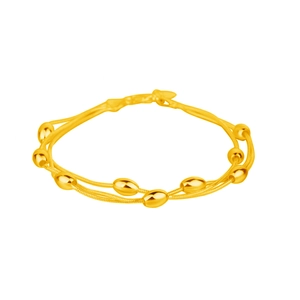 Detail of a double-layered gold snake chain bracelet featuring polished oval beads