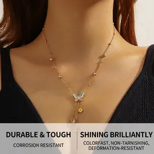 Close-up of gold chain necklace with colorful enamel butterfly and floral drop pendants