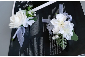 Detailed view of white rose boutonniere and wrist corsage set for wedding ceremonies