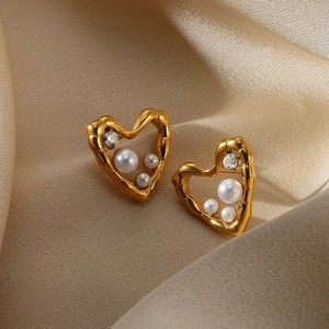 Macro shot of gold heart earring with inlaid white pearls and sparkling zircon