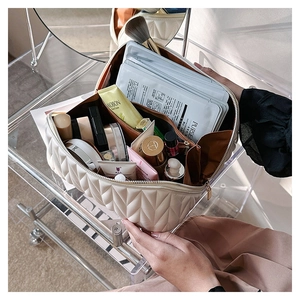 Dettaglio della borsa da toilette trapuntata beige aperta con ampia capacità interna