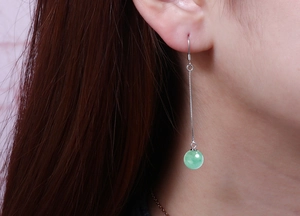Detail shot of long S925 silver earring with light green bead on a female model