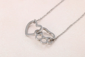 Macro shot of silver heart and pet paw interlocking pendant on fine cross chain
