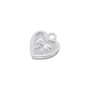 Detailed view of a silver heart pendant with embossed bow design and metallic finish