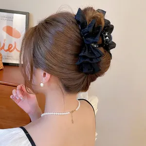 Elegant black pleated tulle hair claw clip for bun hairstyles on a female model