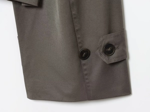 Detailed macro view of dark grey trench coat cuff with button and strap on twill fabric