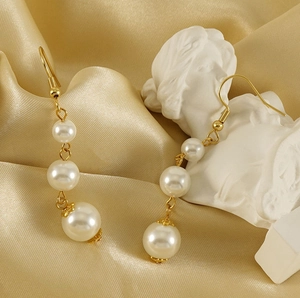 Détail de boucles d'oreilles en or 18k avec trois perles dégradées sur soie jaune