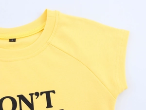 Detailed close-up of yellow knit T-shirt neckline with S size tag and text print