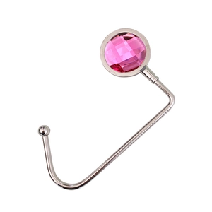 Detail of portable silver metal bag hook with a faceted pink crystal diamond top
