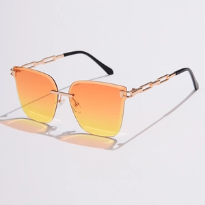 Close-up of golden metal chain temples and orange gradient lenses on rimless sunglasses