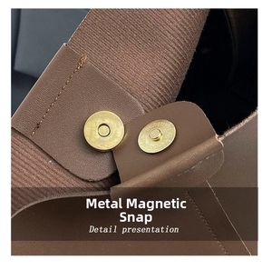 Detail of metal magnetic clasp on brown leather tote bag with striped fabric lining
