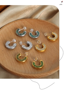 Macro detail of U-shaped earrings with colorful pavé zircons on a wooden display
