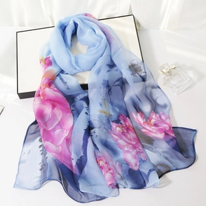 Lightweight blue silk-like scarf with floral prints draped over a white gift box