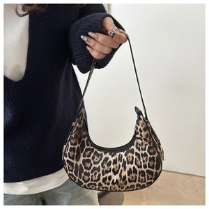 Model holding a vintage leopard print crescent armpit bag with black strap detail