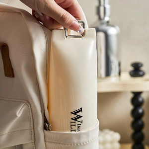 Portable beige travel toothbrush case being tucked into a backpack side pocket
