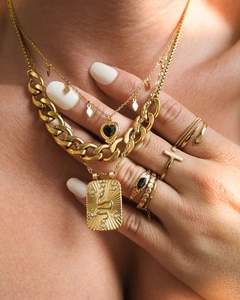 Détail du lot de colliers dorés superposés avec pendentif cœur et breloques serpent