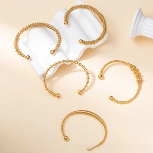 Macro view of five 18k gold plated stainless steel twisted bangles on white stands