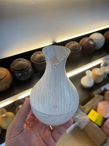 Detail of light wood grain aroma diffuser with vase shape and touch power button