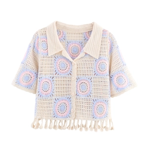 Close-up of crochet knit texture with colorful floral patterns and pom-pom tassel hem