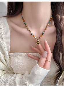 Détail d'un collier de perles bohème avec perles marron-jaunes et pendentif rond doré