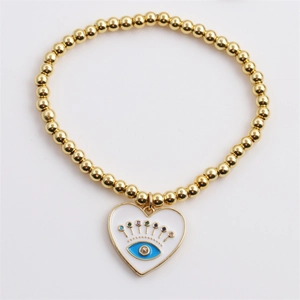 Macro view of gold plated bead bracelet featuring a heart shaped evil eye charm
