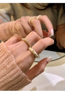 Detail of stacked pearl and beige enamel floral rings on finger with mirror reflection