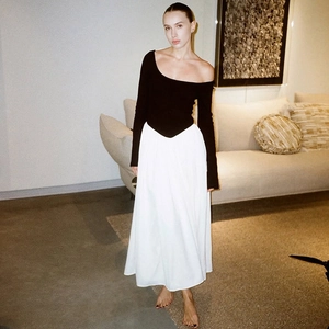 Detail of elegant black off-shoulder long sleeve top paired with white maxi skirt