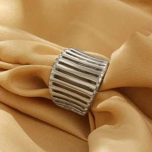 Detail of silver hollow ring with horizontal ribbed texture on golden silk fabric