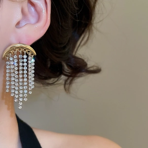 Détail de boucles d'oreilles dorées à pampilles avec des cristaux scintillants sur mannequin