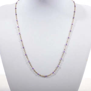 Detail of a thin gold beaded necklace featuring delicate purple enamel beads on a fine chain