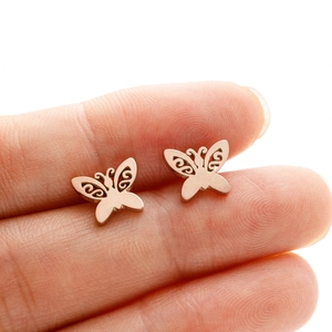 Macro shot of rose gold butterfly earrings showing hollow wing texture and size on finger