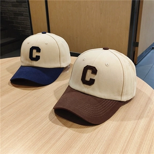 Two-tone baseball caps with large C embroidery in navy and brown on wooden surface