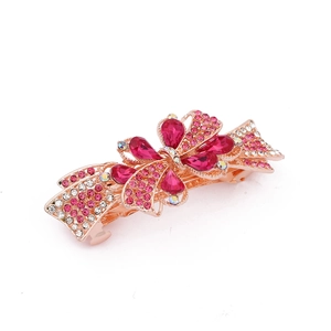 Detailed view of golden bow hair clip with pink and rose red rhinestones in macro