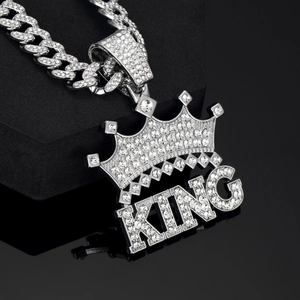 Macro shot of silver Cuban chain necklace with iced out KING crown pendant details