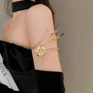 Detail of gold spiral arm cuff featuring a cutout flower and butterfly with rhinestones