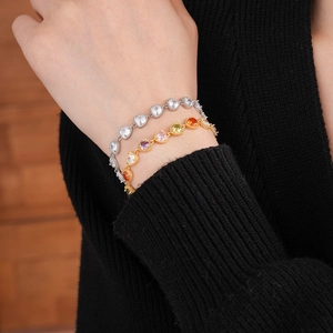 Detail of silver heart zircon bracelet and gold multi-colored gemstone hand jewelry