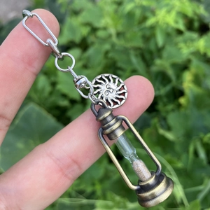 Detailed close-up of a bronze hourglass pendant with sun tag and silver chain