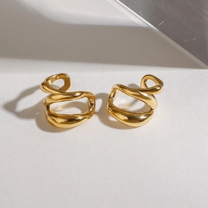 Makro-Detail von geometrischen hohl-goldenen Ohrklemmen mit poliertem Finish und Schatten