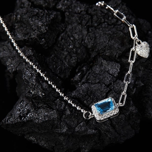 Detail of silver S925 bracelet featuring a blue rectangular gemstone and heart charm