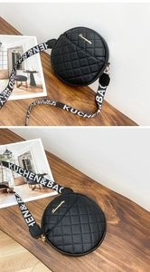 Detail of black quilted round bag with matte PU leather and branded webbing strap