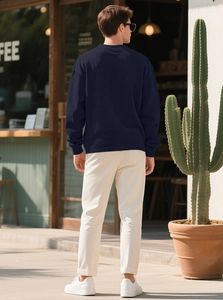 Rear view of man in navy cable knit sweater standing by an outdoor cafe in natural light