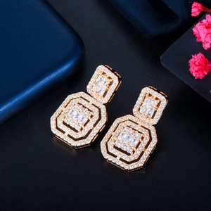 Macro shot of geometric gold earrings with cubic zirconia inlay on a black background