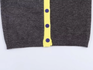 Detail of dark grey knit cardigan with bright yellow placket and purple buttons