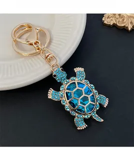Detail of cute turtle keychain with blue crystals and faceted gemstone on golden metal