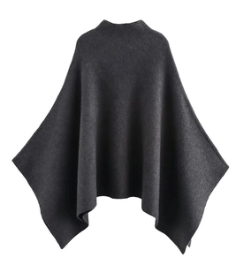 Detail of dark grey knit poncho featuring a high neck and soft minimalist texture
