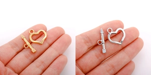 Macro view of heart-shaped OT toggle clasps in gold and silver finish on palm