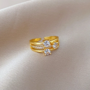 Macro shot of gold triple-layered ring with zircon stones on champagne satin fabric
