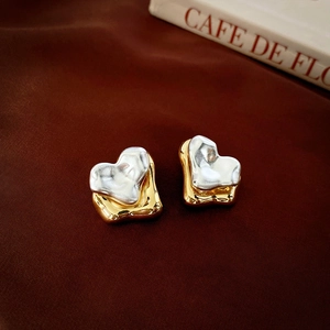 Macro shot of two-tone heart stud earrings with gold and silver layered metallic finish