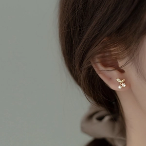 Close-up of model wearing gold cherry pearl stud earrings with sparkling zircon detail