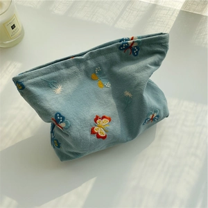 Macro detail of blue butterfly embroidery on a soft fabric cosmetic organizer bag